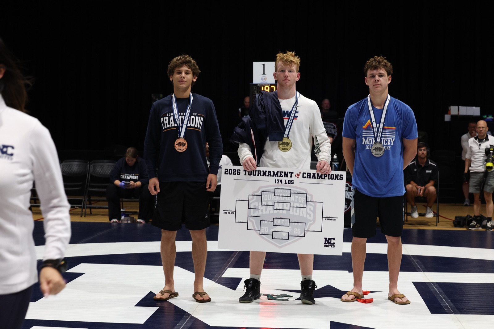 The 174 lb podium at the 2026 Tournament of Champions — the three placers on the mat, the champion holding the bracket