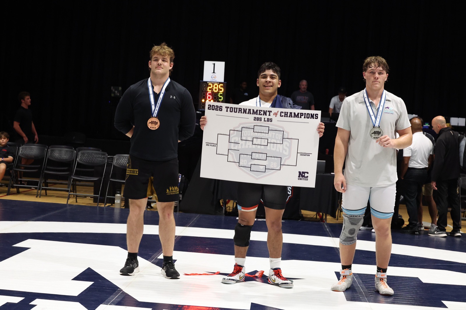The 285 lb podium at the 2026 Tournament of Champions — the three placers on the mat, the champion holding the bracket